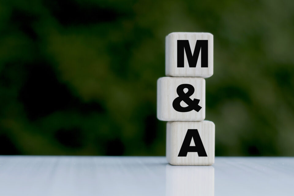 The concept of the word M&A on cubes on a beautiful green background. Business concept