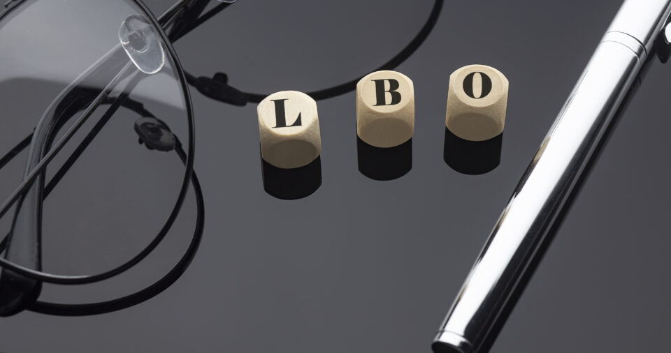 LBO concept, words on wooden blocks on black background with pen and glasses.