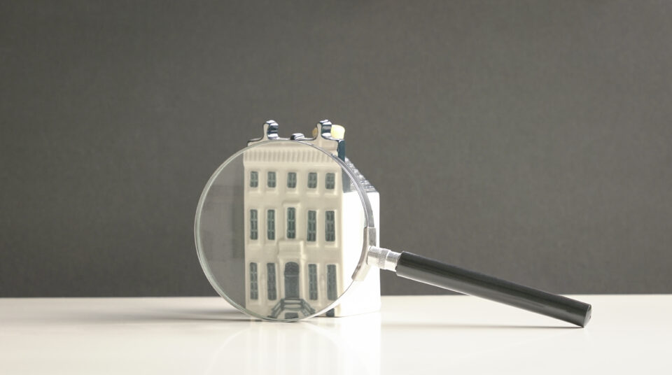 Mini property with magnifying glass. Search for property concept.