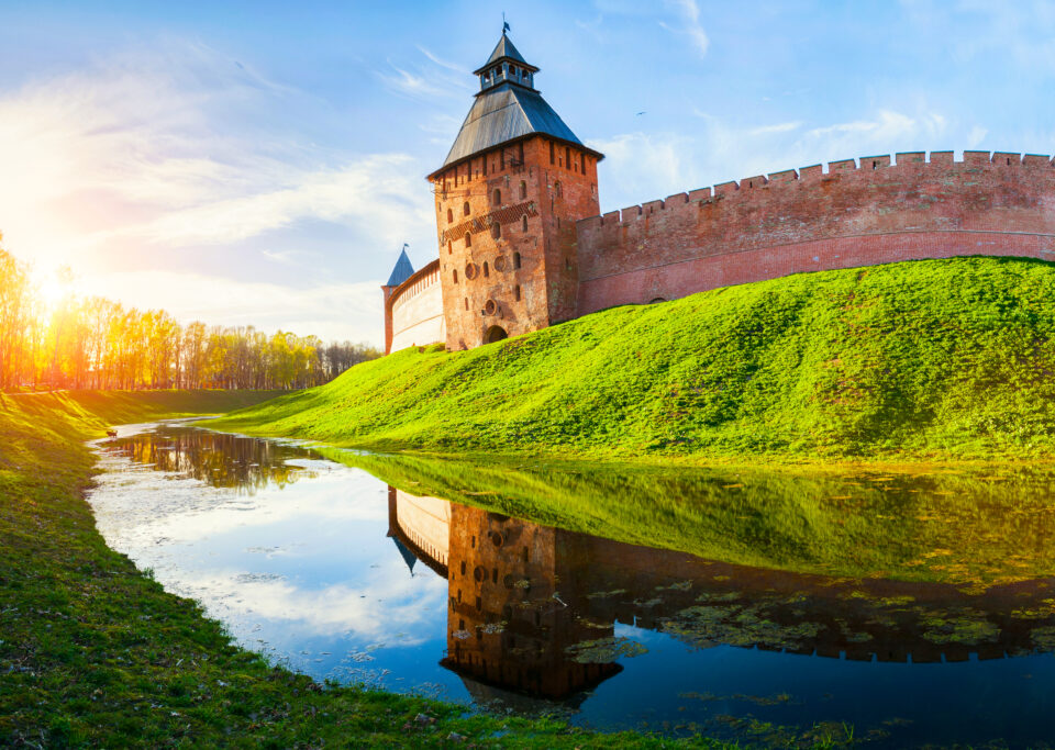 Veliky Novgorod Kremlin - Savior tower reflecting in the water moat in Veliky Novgorod, Russia, travel sunset landscape of Veliky Novgorod